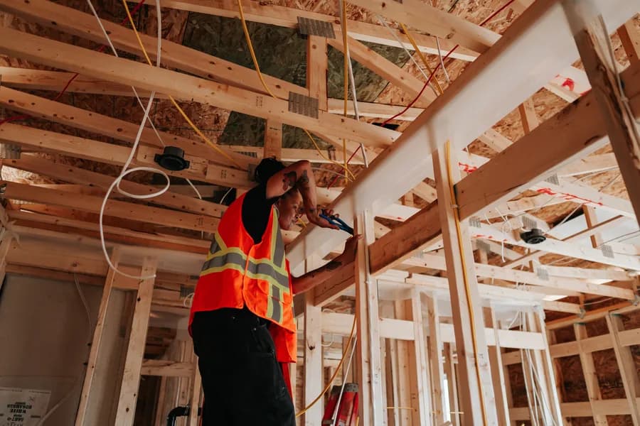 A Herauf tradesperson running electrical through the ceiling framing of a module