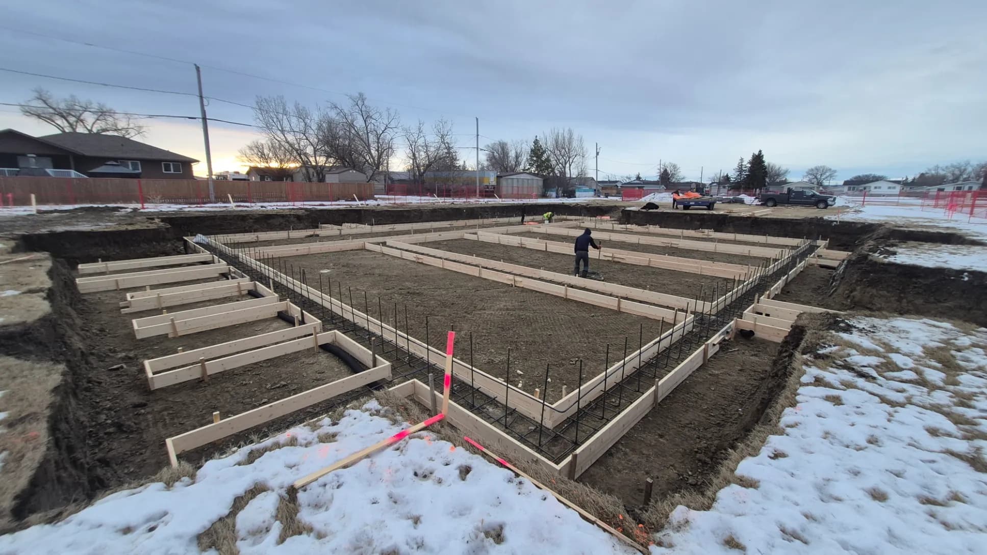 Formwork and rebar laid out across an excavated foundation at first light