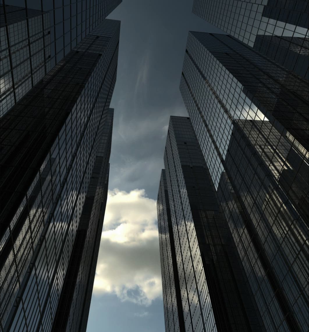 Looking up between glass towers at a clouded sky