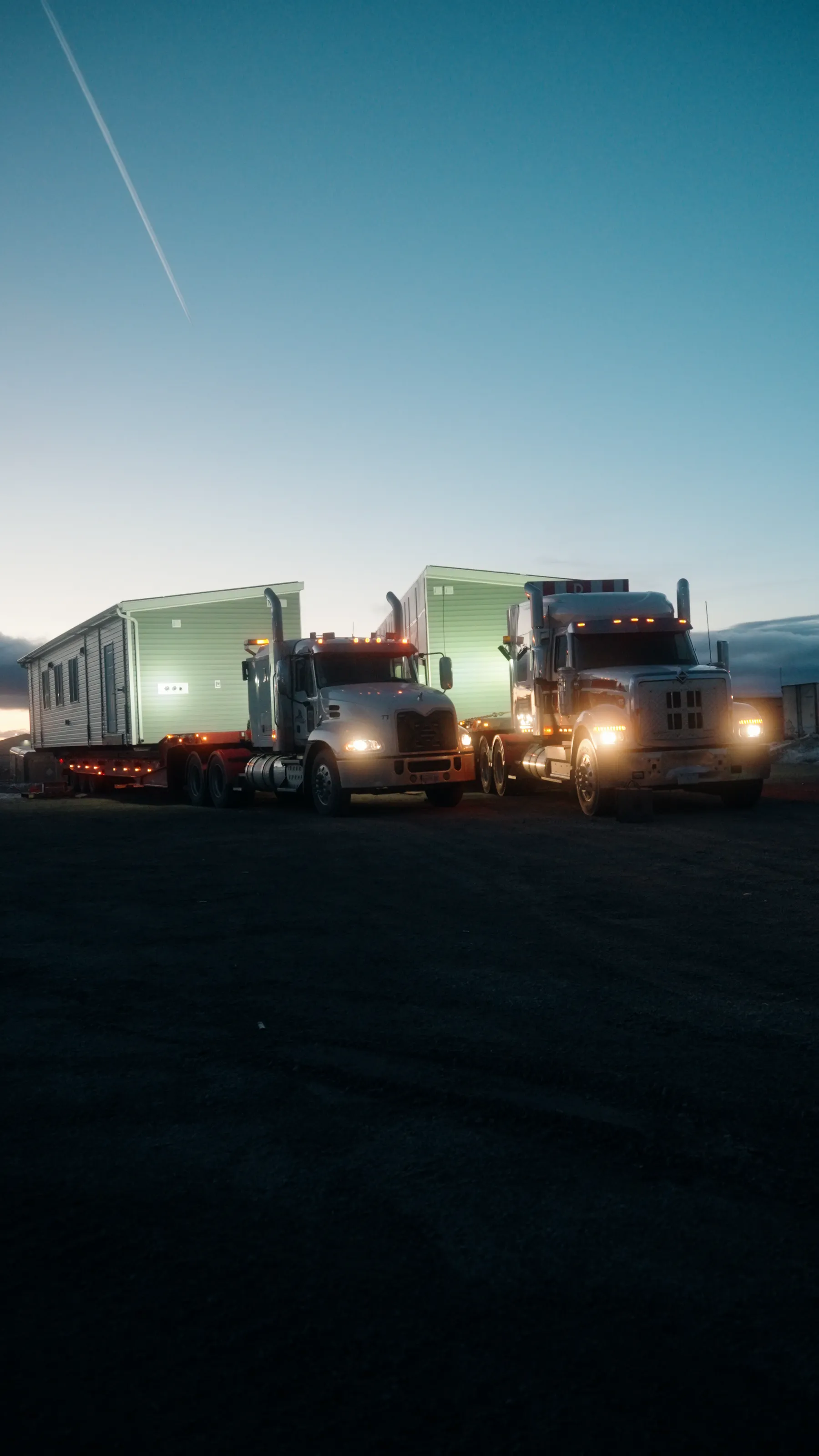 Two Herauf modular units on trucks leaving the yard at dawn