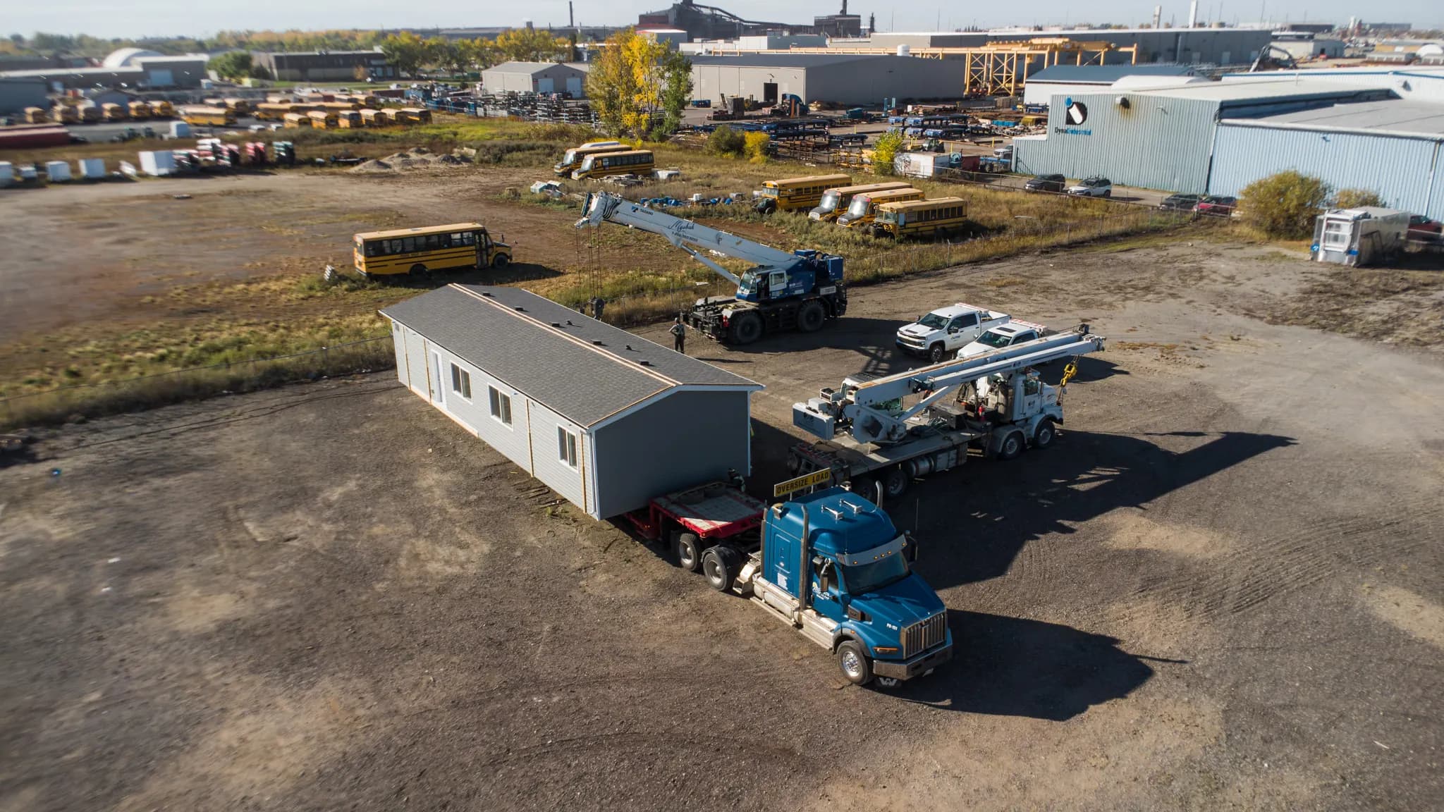 Drone view of the yard with the module loaded on the trailer and the truck hitched, cranes still beside it