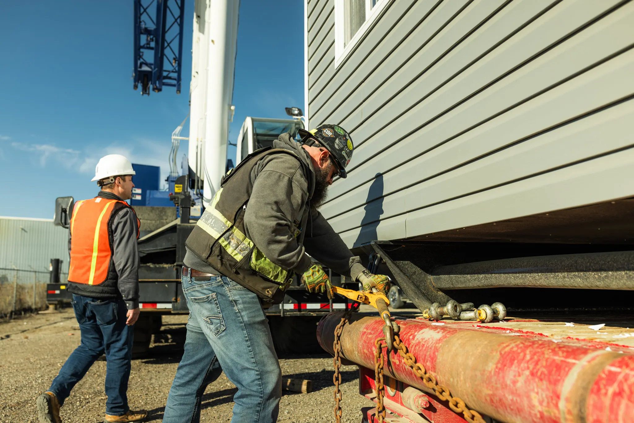 A crew member tightening chain binders that tie the module down to the trailer