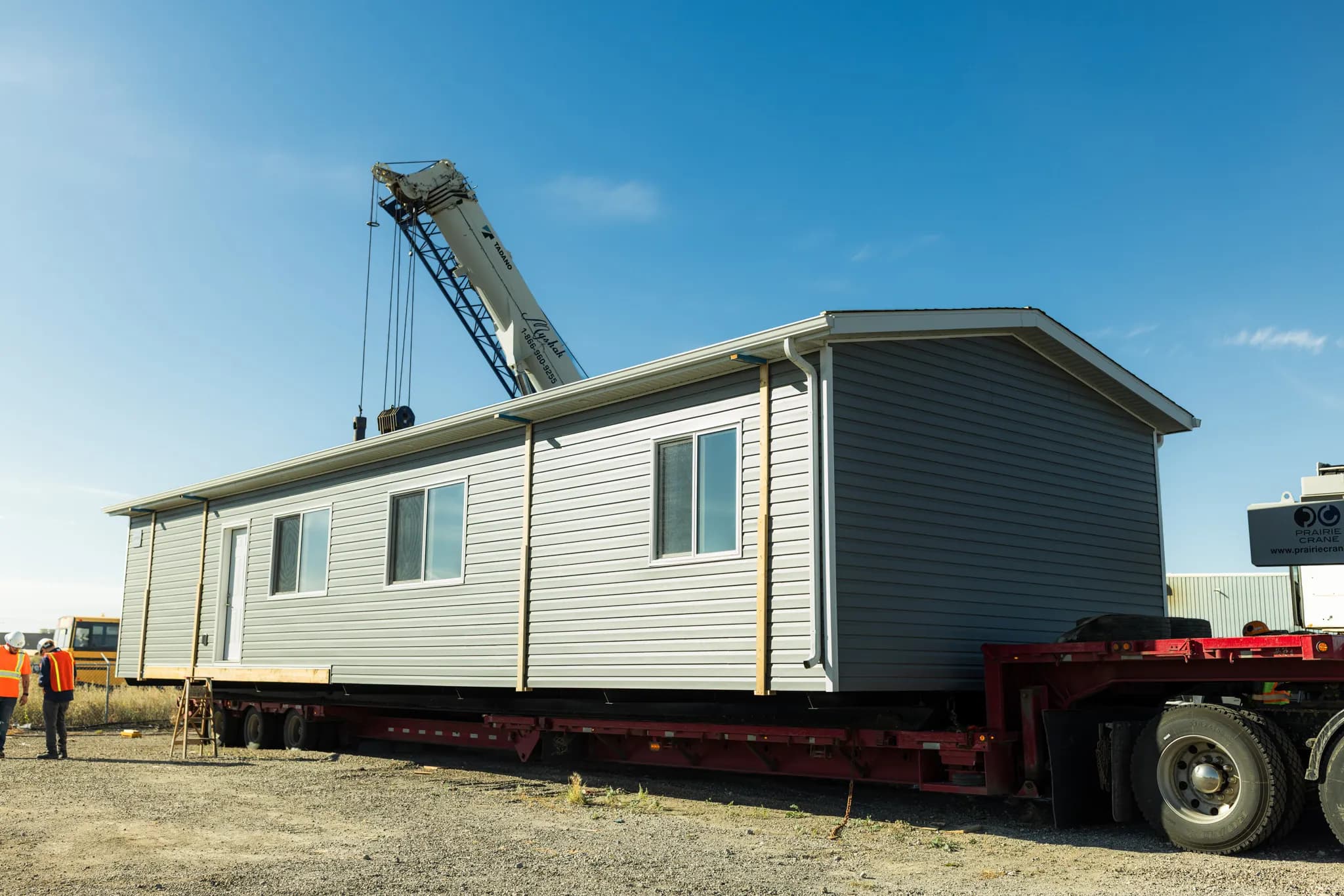 The finished Herauf module sitting on a red lowboy trailer, a crane boom behind it
