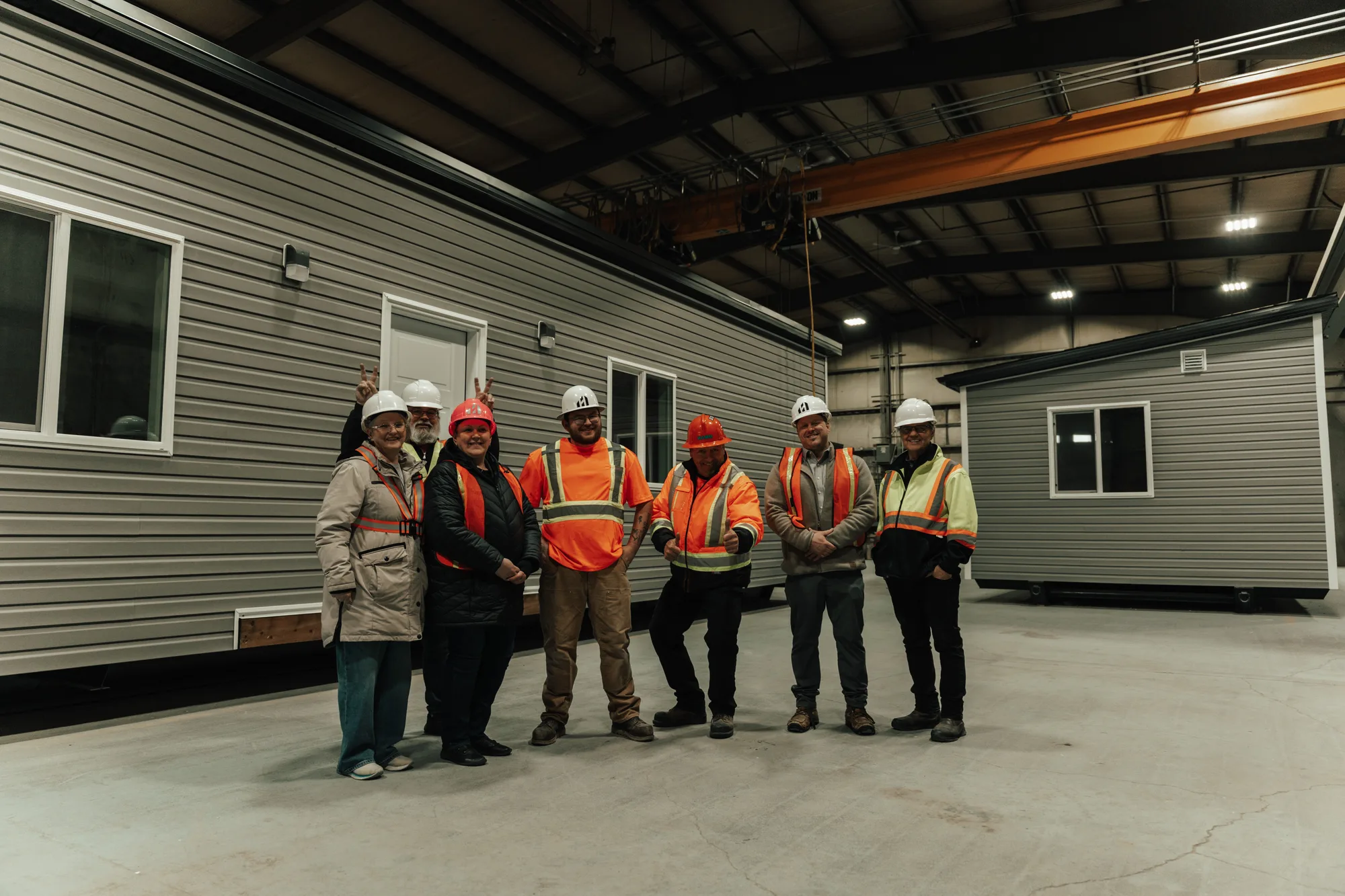 The Herauf Modular crew in hard hats and high-visibility gear beside two finished modules on the Zehner plant floor