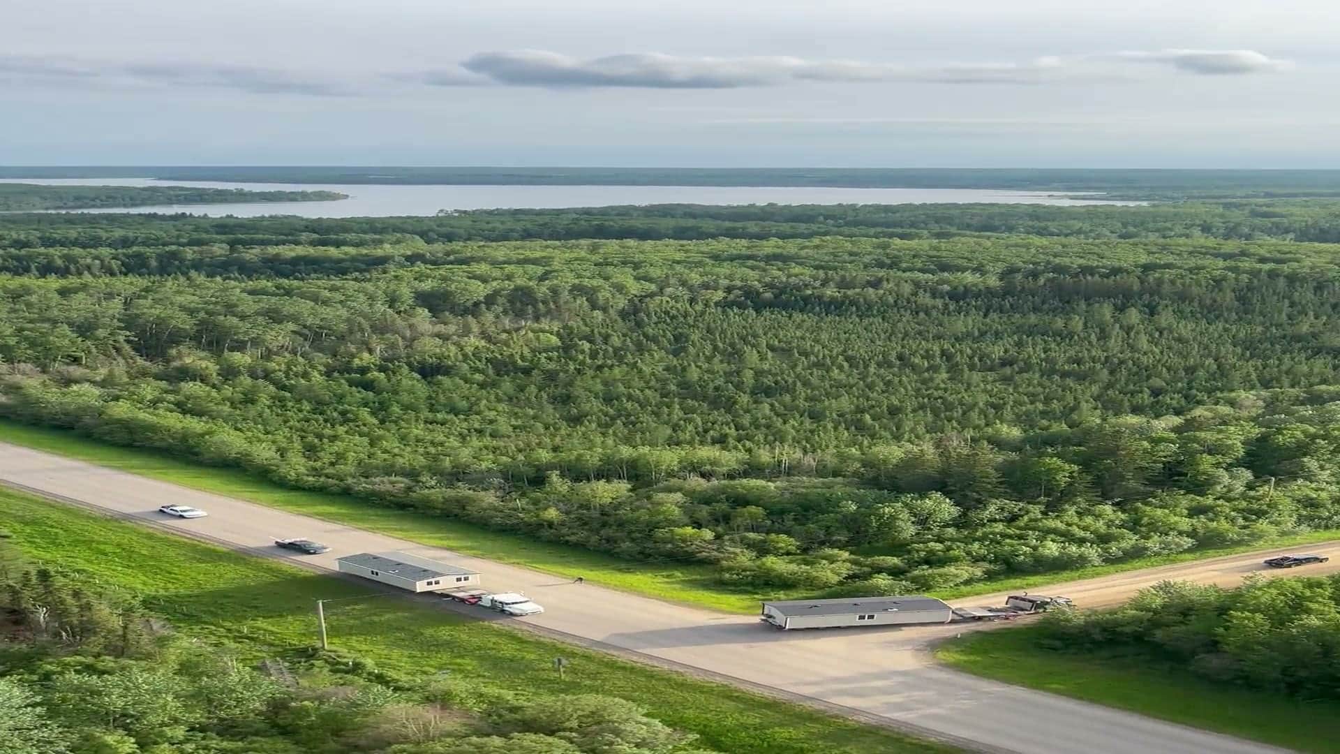 An aerial view over northern boreal forest, a lake and a highway