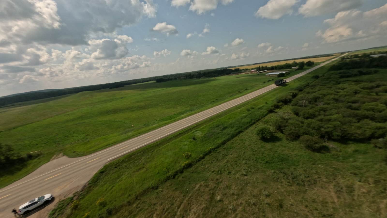 Aerial view of a Herauf modular home delivered by truck through summer prairie