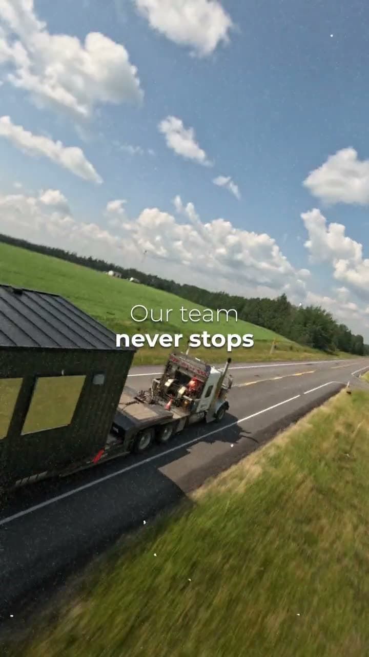 Dark modular unit with yellow window covers on a truck on a highway through green hills
