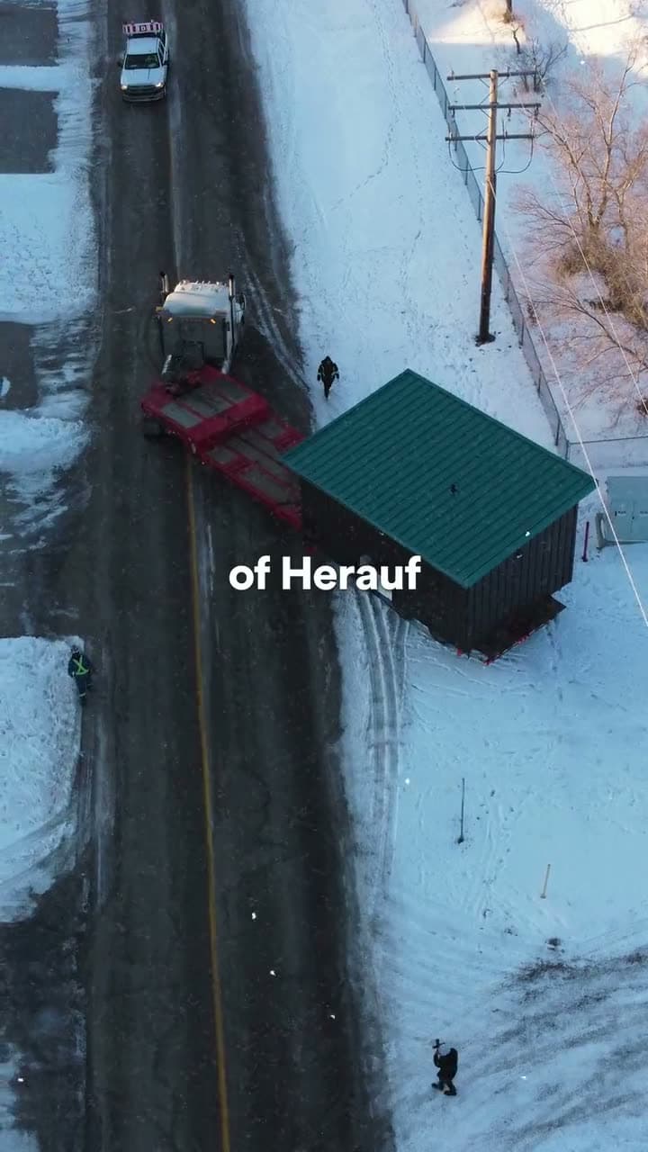 Overhead view of a truck towing a green module down a snowy street