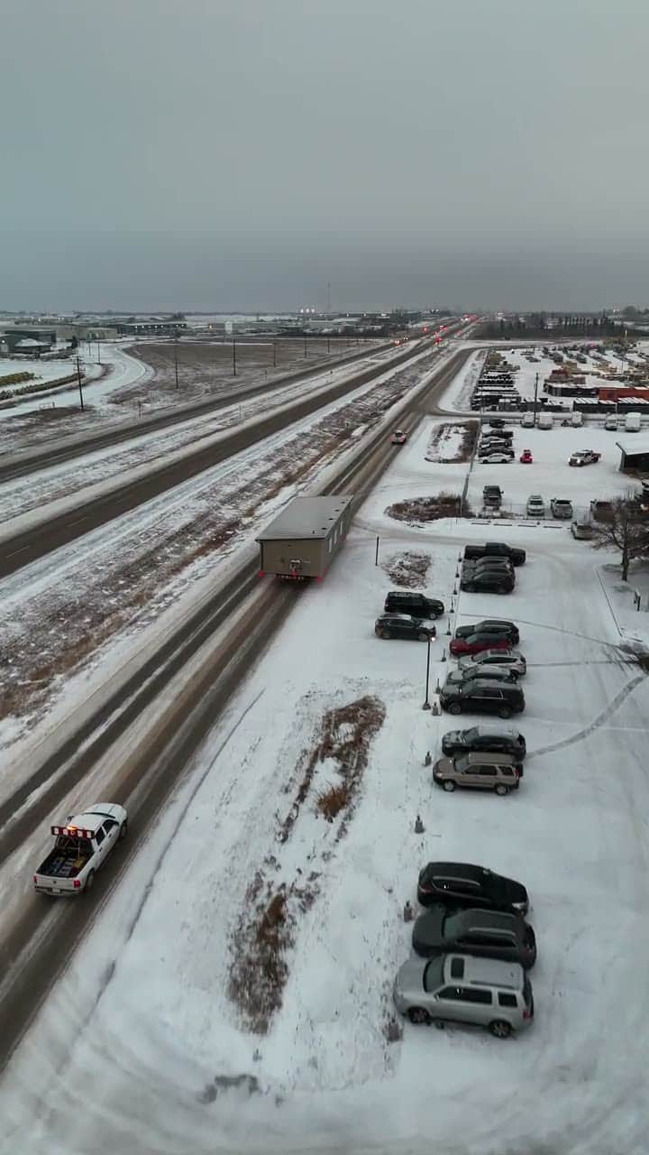 A finished modular building on a snowy highway behind its escort truck