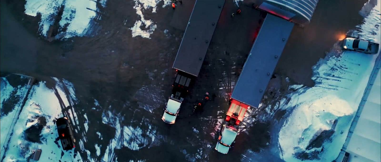 Finished homes backed up to trucks in a snowy yard at dusk, ready for delivery